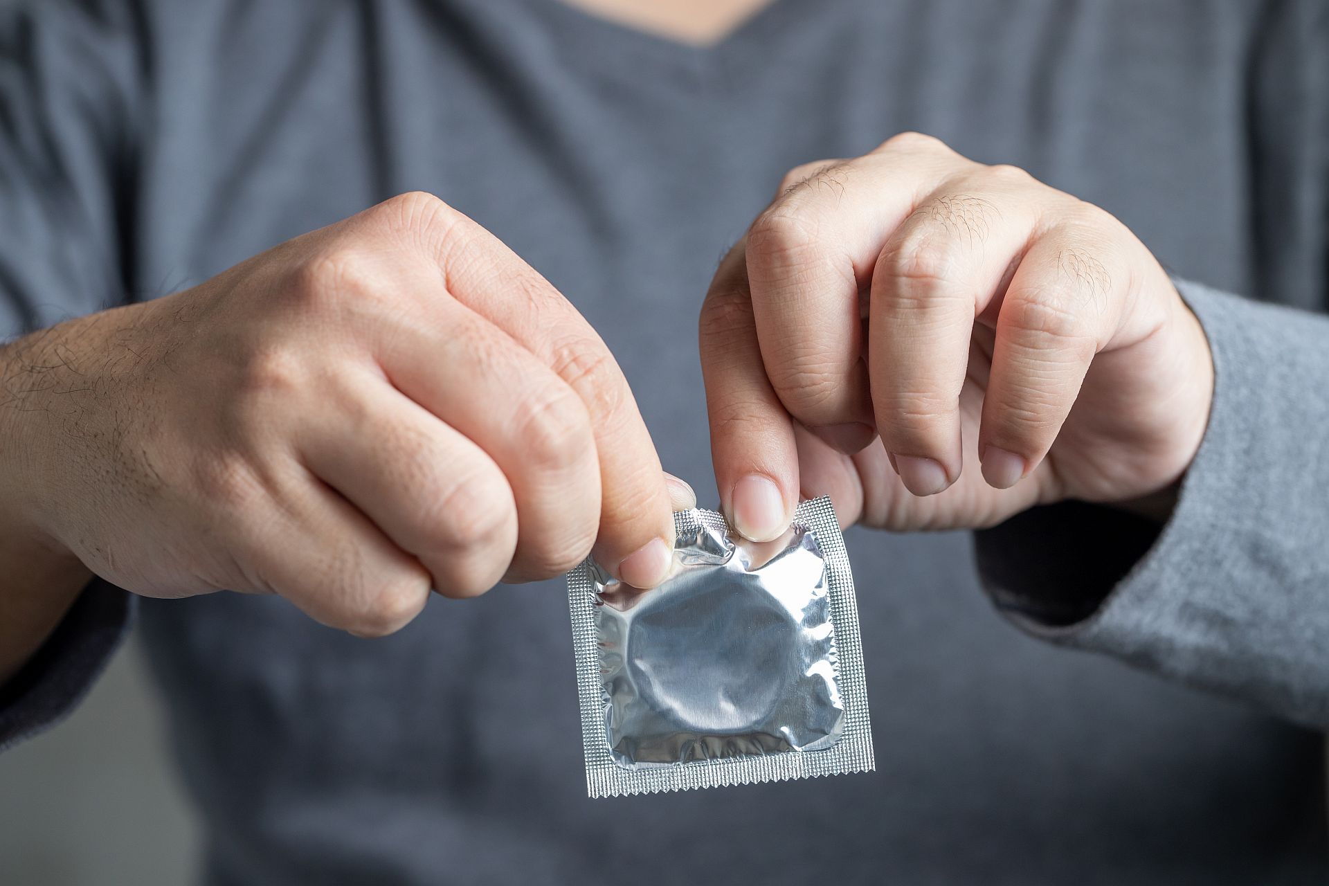 Mężczyzna otwiera prezerwatywę